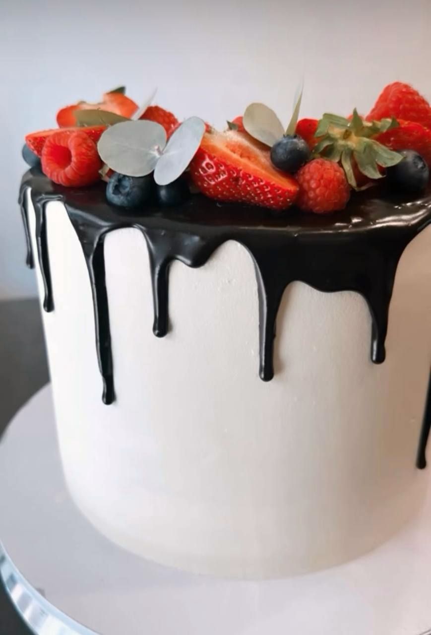 White cake with chocolate drip and fresh berries