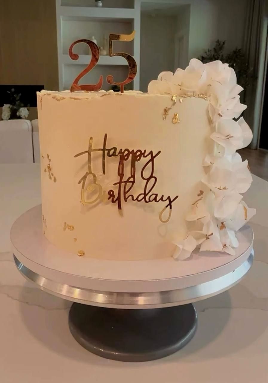 Cream birthday cake with a gold 25 topper and white flowers