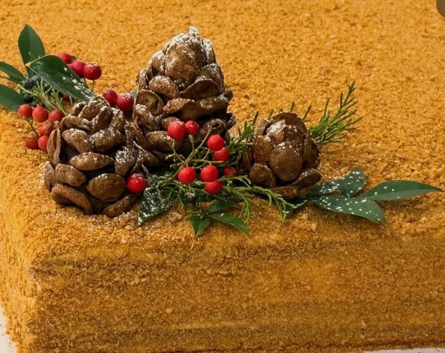 Honey cake topped with chocolate pine cones and berries